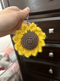a person holding a crocheted sunflower keychain